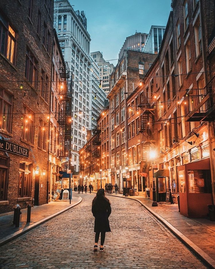 Stone Street's cobblestones and brick buildings under glowing string lights